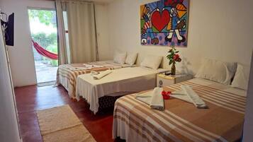 Habitación de hotel con dos camas, un cuadro, una ventana con cortinas y una hamaca roja en el exterior.
