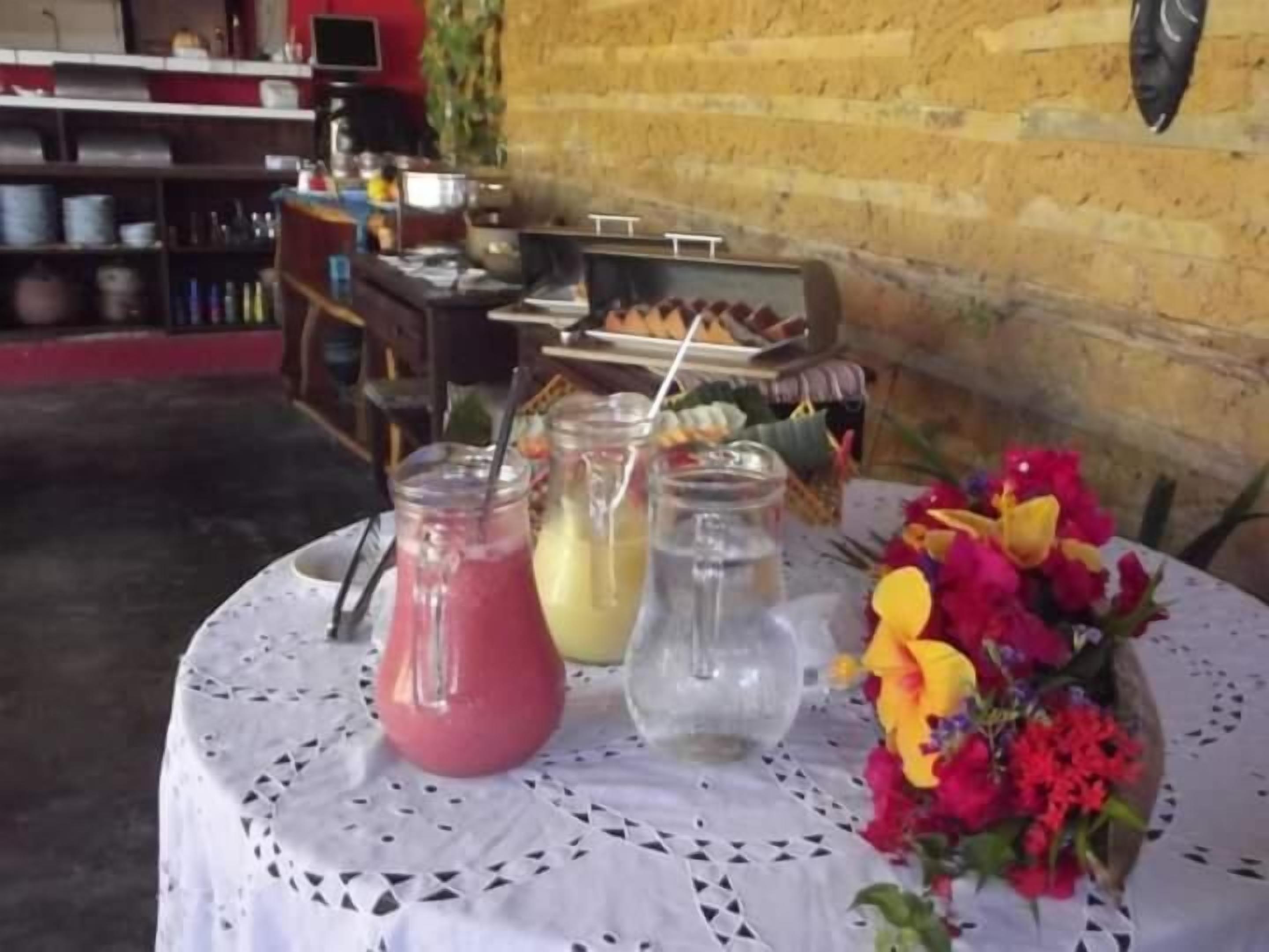 A table with drinks and a floral arrangement, set against a brick wall.