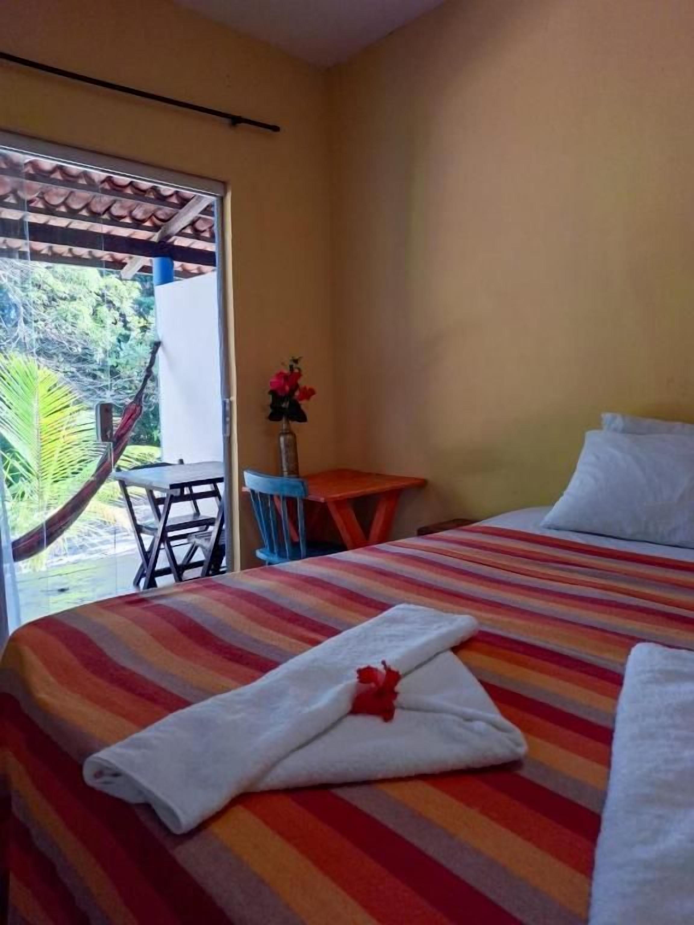 Habitación de hotel con cama, una mesita, una silla y una hamaca fuera de la ventana.