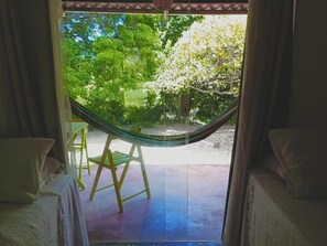 A hammock chair in a room with a view of a garden. - Pousada dos Mundos (Conde)