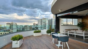 En modern takterrass med utsikt över staden, trägolv och moderna möbler.