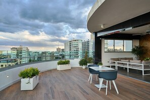 En moderne tagterrasse med udsigt over byen, trægulv og moderne møbler.