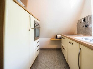 Eine kompakte Küche mit eingebautem Backofen, einer Arbeitsplatte mit Toaster und Fliesenboden.