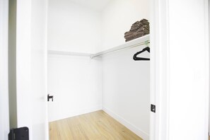 A narrow hallway with a wooden floor, a white door, and a closet with a hanging rack. - *New* Naples Villa w/ Pool Jacuzzi | Sleeps 14 (Naples)