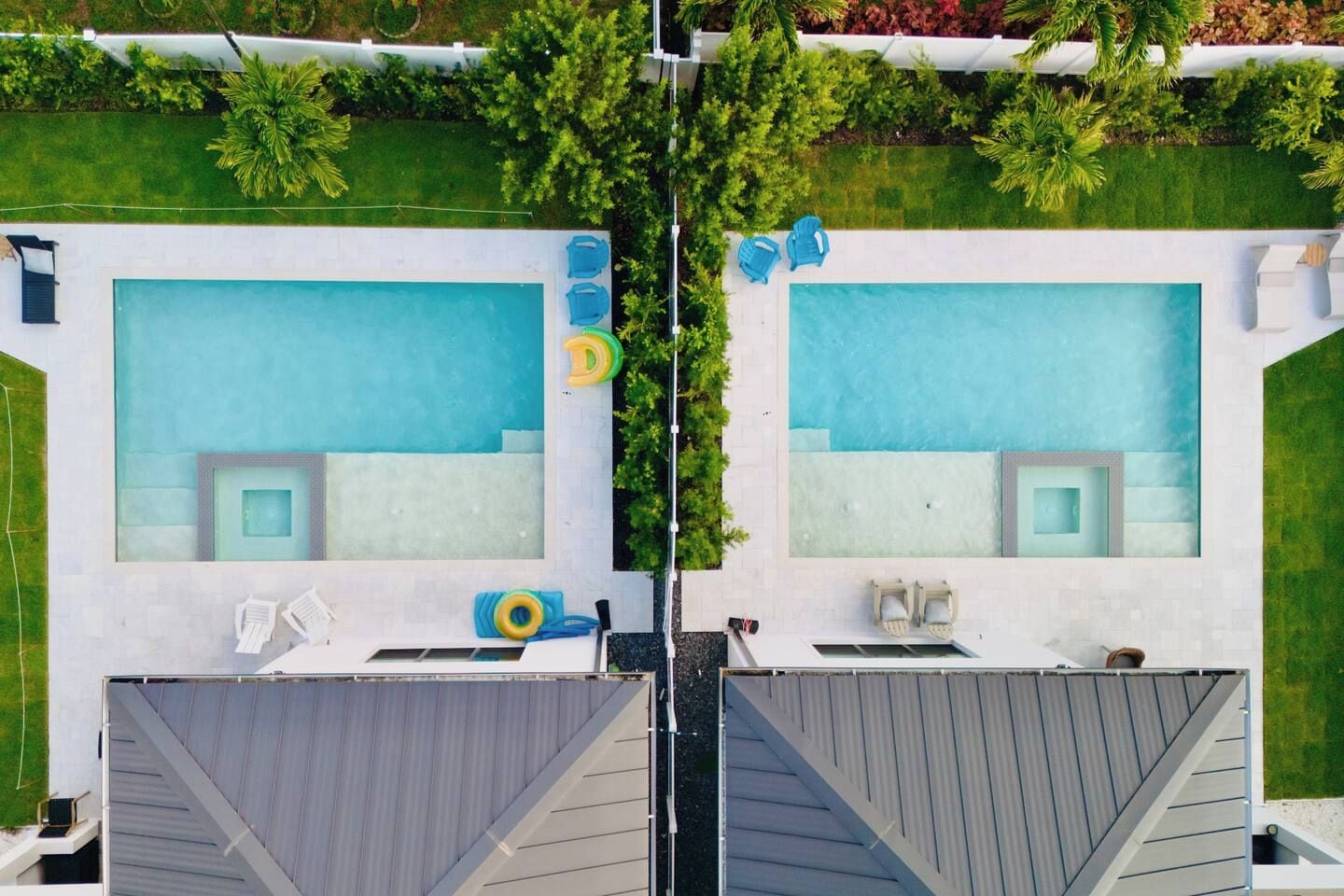 Une piscine sur le toit, divisée en deux espaces distincts, chacun comprenant un petit coin salon et un élément décoratif aquatique.