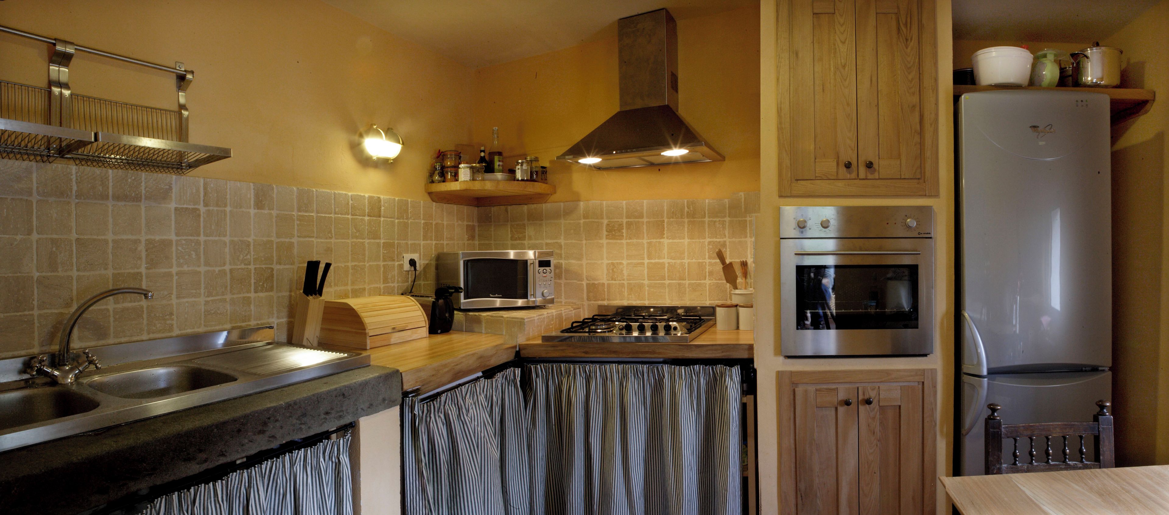 A kitchen with a stainless steel sink, a microwave, an oven, and a refrigerator.