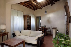 A cozy living room with a sofa, a wooden table, a cabinet, and a hanging light fixture. - Villa in Tuscany, private pool, Wi-Fi, parking, pet-friendly, in the woods (Toscana)