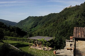 A rustic stone building with a tiled roof, surrounded by lush greenery and a hillside. - Villa in Tuscany, private pool, Wi-Fi, parking, pet-friendly, in the woods (Toscana)