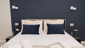 Un letto rifatto con due cuscini, un comodino con un telefono e un vaso con un fiore.