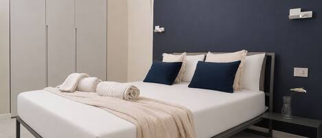 A modern bedroom with a bed, bedside tables, and a wardrobe.