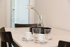 Een eettafel met een vaas, twee kopjes en twee glaasjes.