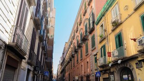 Una stretta via fiancheggiata da edifici, con un attraversamento pedonale e un'auto bianca parcheggiata a destra.