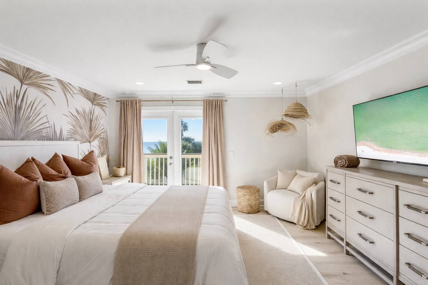 Un dormitorio con cama, televisor, ventilador de techo y vistas al exterior.