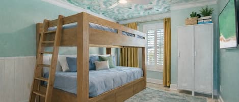 A bunk bed with a ladder, a ceiling fan, a window with curtains, and a wardrobe.
