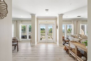 A spacious living area with a balcony, a dining area, and a seating arrangement with a sofa and chairs. - Coastal Cabana• Private Pool• Ocean View• Near 30A (Panama City Beach)