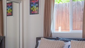 Un dormitorio con cama, ventana con cortinas, puerta y una pared con un cartel.