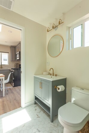 A bathroom with a toilet, sink, and mirror. There is a window above the mirror. - Private Casita in Lake Balboa w/ Gate & Backyard (Los Angeles)