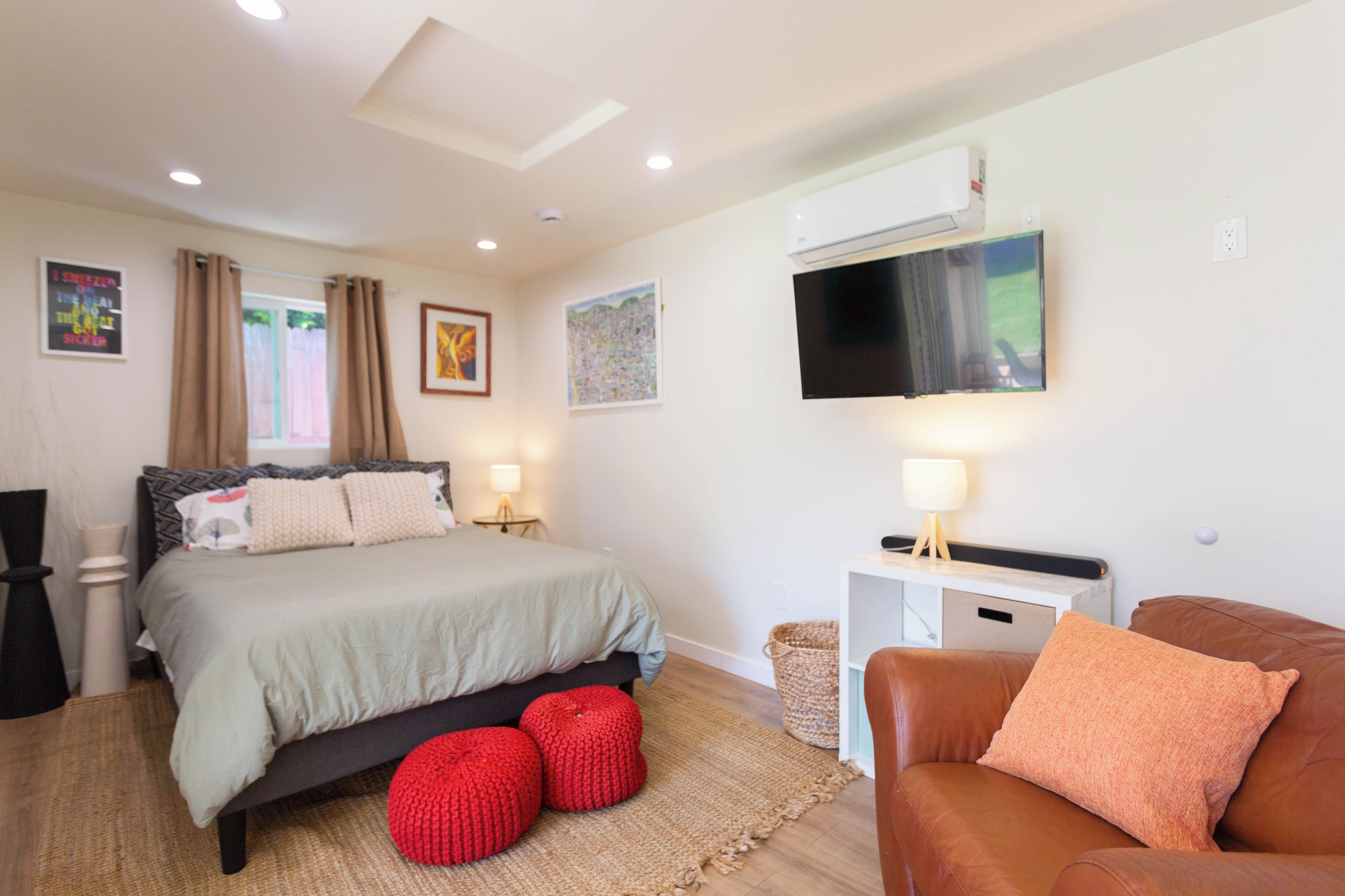 A modern bedroom with a bed, a TV, a desk, and a couch.
