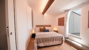 A bedroom with a bed, bedside lamps, a window, and a view of the outside. - Vrbo Property (Firenze)