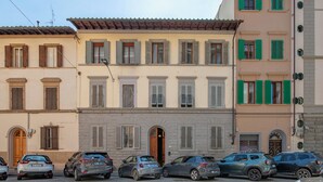 A row of parked cars in front of a building with multiple windows and a central entrance. - Vrbo Property (Firenze)
