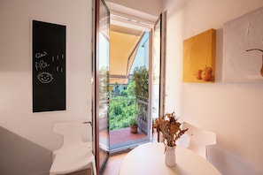 Ein modernes Badezimmer mit einem weißen Waschbecken, einer Tafel mit Schrift und Blick auf einen Balkon mit Grünpflanzen.