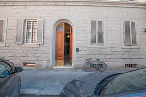 A building with a wooden door, two windows with shutters, and a bicycle parked outside. - House Giotto 33 (Firenze)