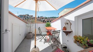 A balcony with a table and chairs, a potted plant, and a hanging planter. - Vrbo Property (Firenze)