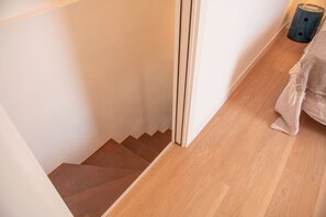 A wooden staircase leading to a room with a light-colored floor. - House Giotto 33 (Firenze)