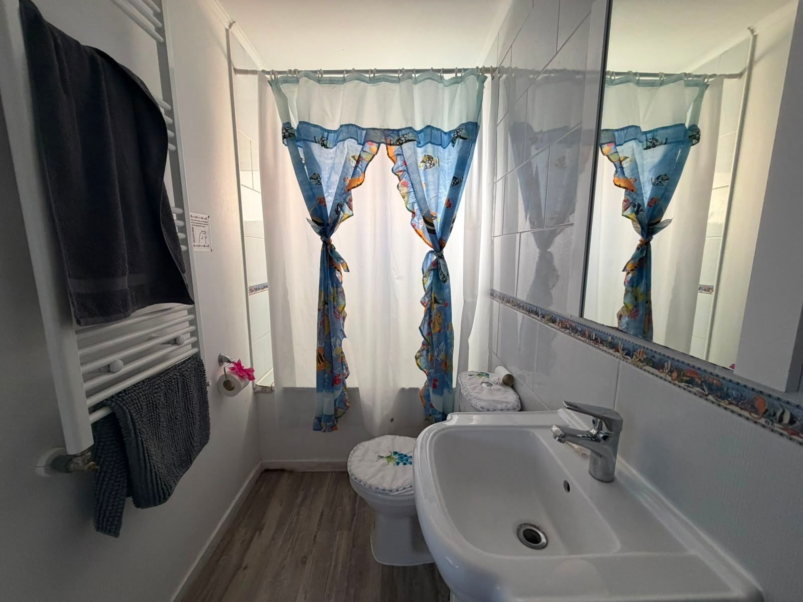 Un baño con inodoro, lavabo y cortina de ducha estampada con motivos florales.