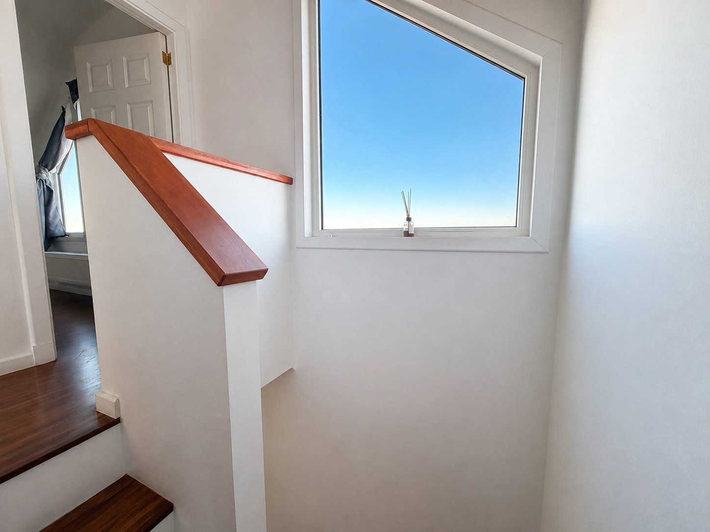 A staircase with wooden handrails leading to a landing with a window.