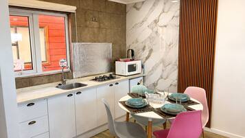 A compact kitchen with white cabinets, a built-in microwave, a gas stove, and a dining area with a table set for four.