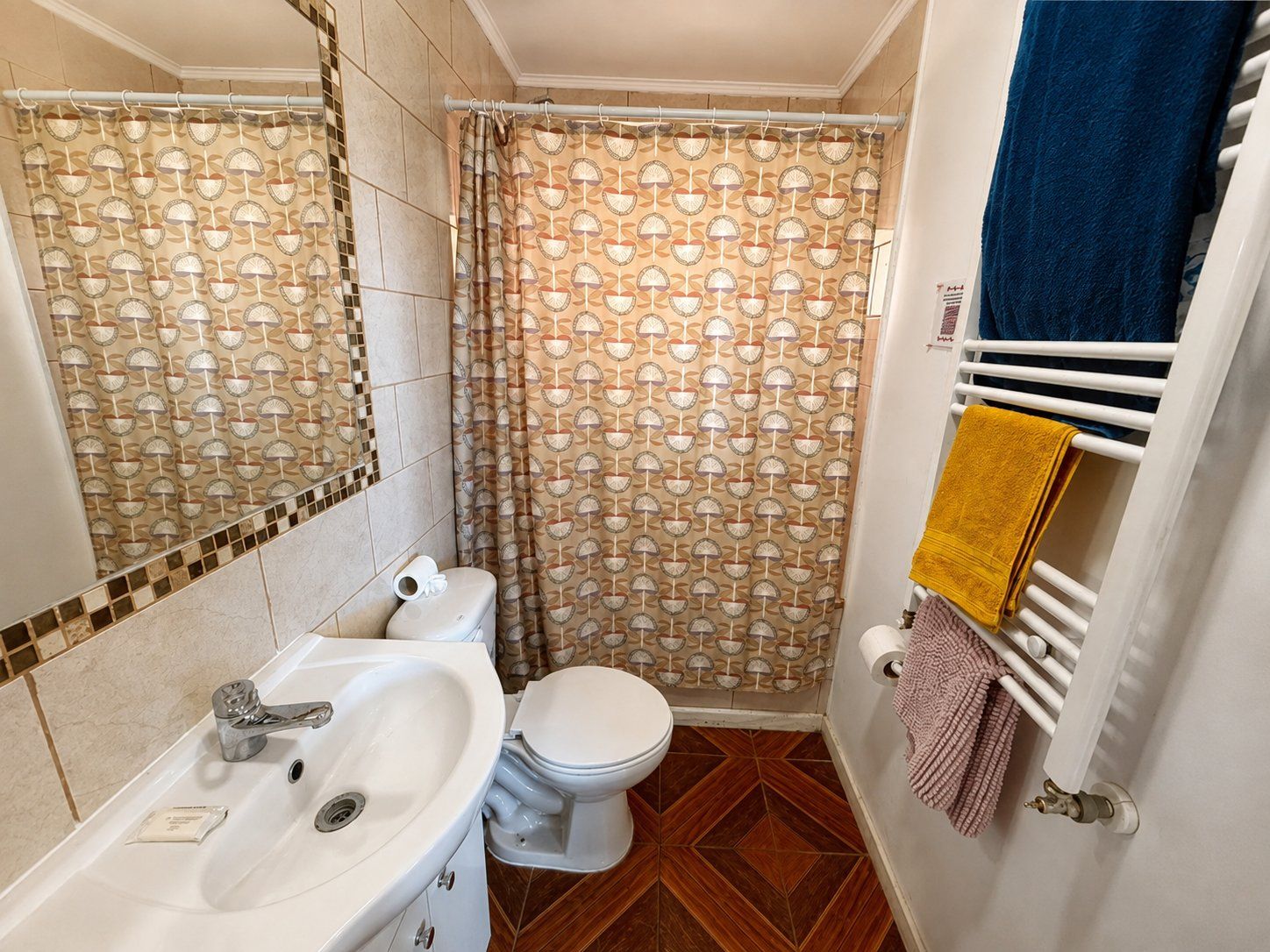 A bathroom with a white sink, toilet, and shower curtain with a geometric pattern.