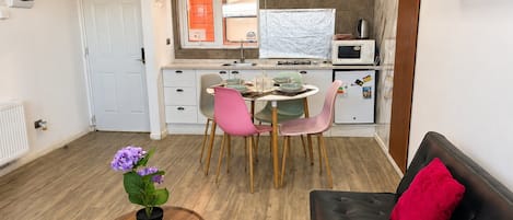 Ett kompakt bostadsutrymme med ett litet kök, en matplats och en sittgrupp.