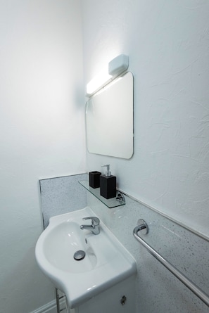 A bathroom with a white sink, a mirror, a soap dispenser, and a hand dryer. - The Stanley Arms Hotel by Guestz (Seascale)