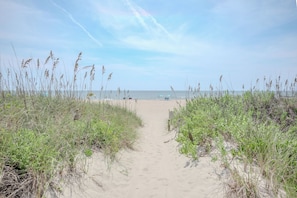 A sandy beach path leading to the ocean with sparse vegetation on either side. - Casa De Ava: Ocean Views and Easy Beach Access (Oak Island)