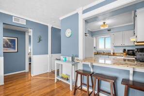 A kitchen with a wooden island, white cabinetry, and a blue wall. - Casa De Ava: Ocean Views and Easy Beach Access (Oak Island)