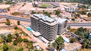 Un hôtel à plusieurs étages doté d’une piscine, situé près d’une route et d’un stade.