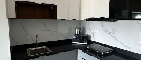 Una cocina moderna con armarios blancos, encimera negra, microondas integrado y estufa.