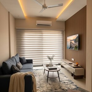 Una sala de estar moderna con un sofá, una mesa de centro y un televisor montado en la pared.