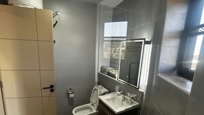 Une salle de bain moderne équipée de toilettes, d’un bidet et d’un lavabo.