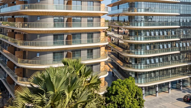Un immeuble résidentiel moderne à plusieurs étages, doté de balcons, de grandes fenêtres et d’une conception architecturale aux lignes courbes.