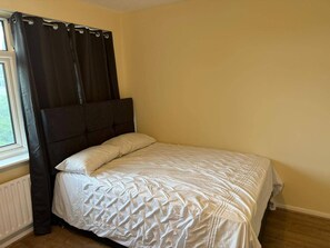 A bedroom with a bed, curtains, and a window. - Spacious 6 Bedroom Home for Families&contractors (Hornchurch)