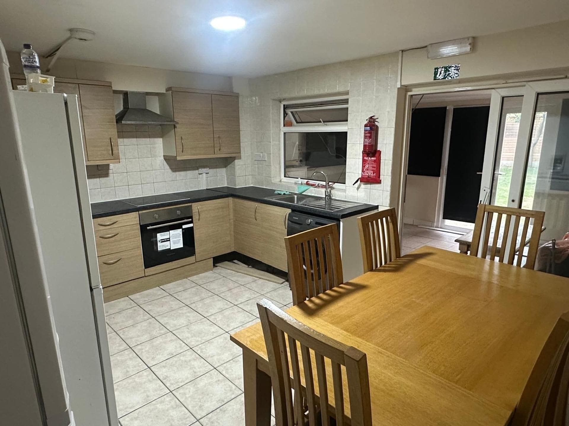 A kitchen with a dining table and chairs, a dishwasher, and a fire extinguisher.