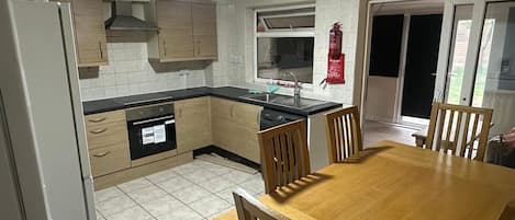 A kitchen with a dining table and chairs, a dishwasher, and a fire extinguisher.