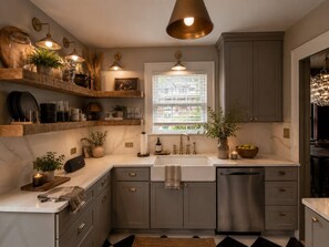 A kitchen with a built-in dishwasher, a window with blinds, and a pendant light above the sink. - NEW! Plaza Social House, GAME ROOM + walkable (Charlotte)