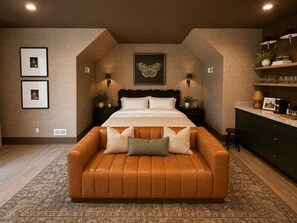 A bedroom with a large bed, a sofa, and a wall-mounted TV. - NEW! Plaza Social House, GAME ROOM + walkable (Charlotte)