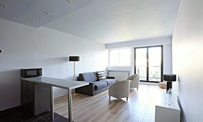 Un espai de viure modern amb zona de menjador, sofà i un gran finestral que proporciona llum natural.