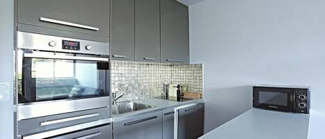Una cocina moderna con electrodomésticos de acero inoxidable, incluyendo horno, microondas y lavavajillas.