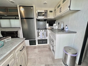 A compact kitchen with a refrigerator, microwave, stove, and sink. - Awesome recreational vehicle on a gorgeous plot of land! Very private and safe. (Aguadilla)