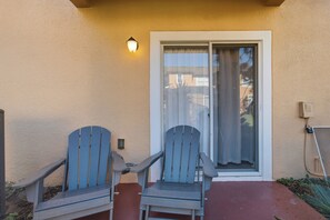 Eine Terrasse mit zwei Adirondack-Stühlen und einer Schiebetür.